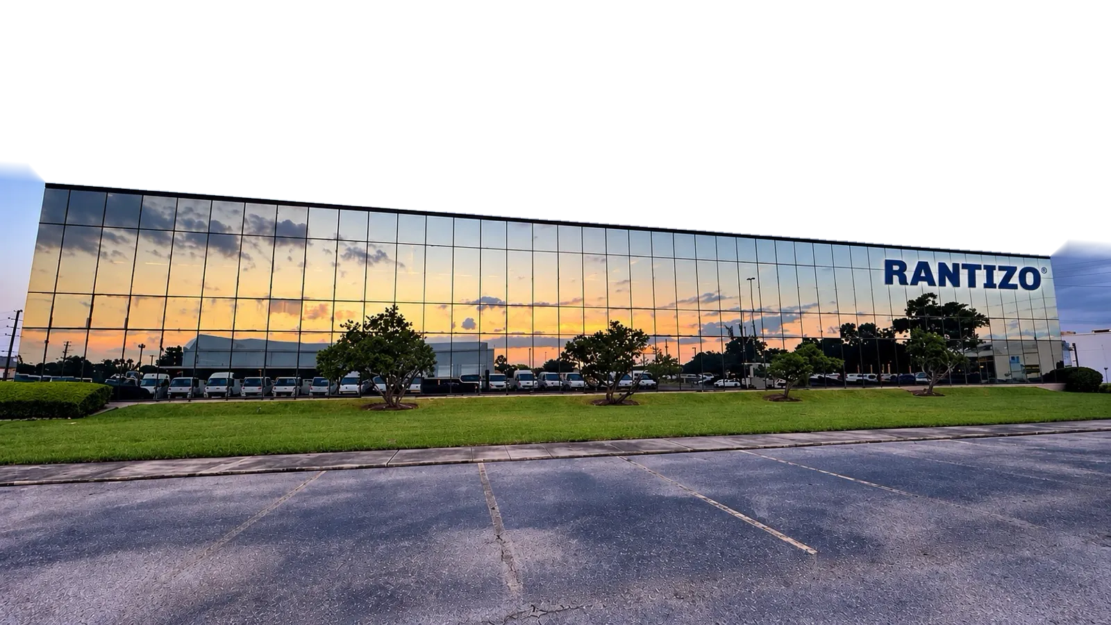 A mirrored-glass building with the Rantizo name on its facade, reflecting the sunset at dusk