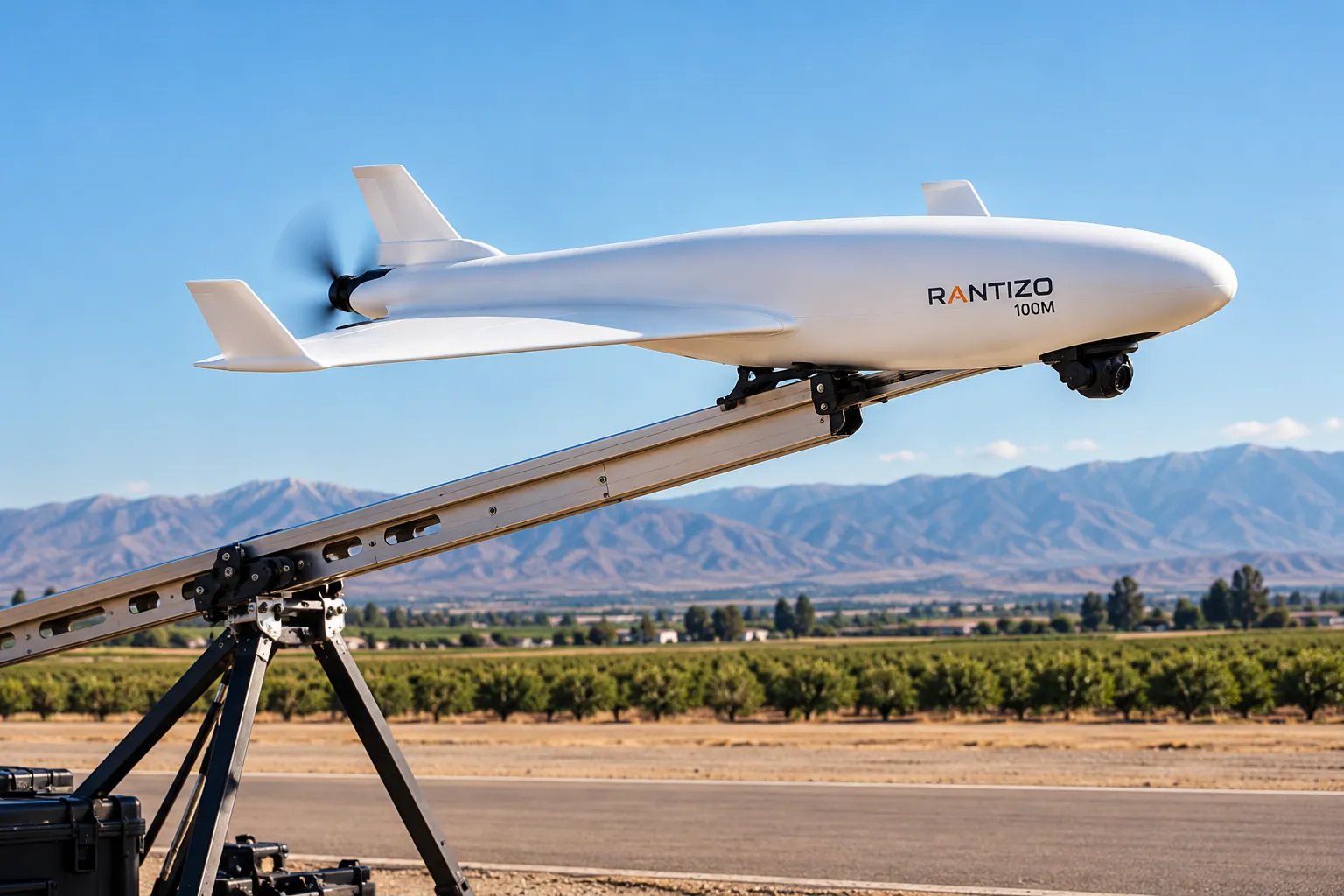 The fixed-wing prototype on a launch rail, propeller turning, a camera turret under its nose